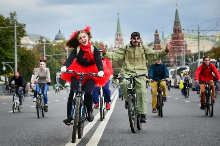 Девушка и парень в карнавальных костюмах во время велопарада в Москве едут рядом с Кремлем