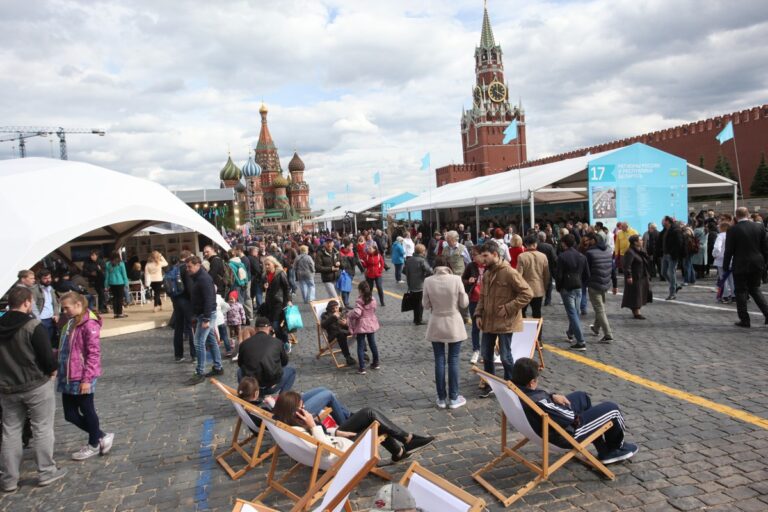 Сидящие в шезлонгах посетители около книжных палаток во время работы книжного фестиваля на Красной площади