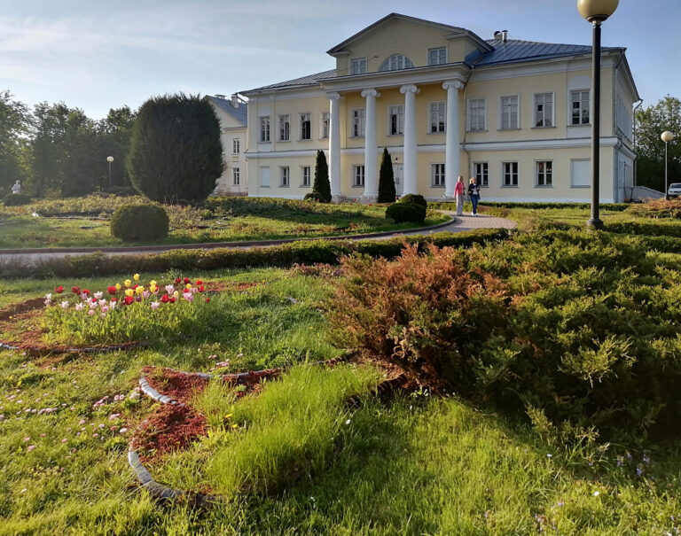Господский дом с колоннами и портиком, клумба с цветами перед ним и гуляющие люди - усадьба Свиблово в Москве